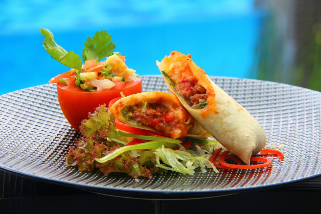 Tasty burrito served with fresh tomato salsa and vibrant veggies, perfect for a flavorful meal.